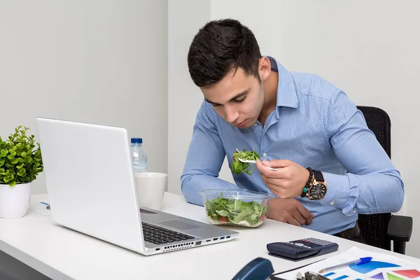 Man eating salad in office