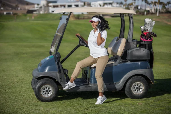Woman in golf buggy speaking on phone