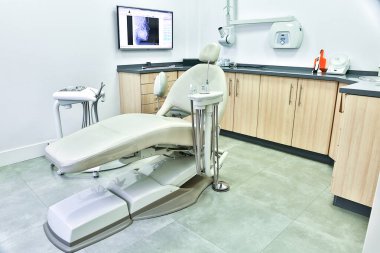 Dolapların yanında bulunan rahat koltuklar ve modern klinikteki dişçi muayenehanesinde baş röntgeni olan monitörler.