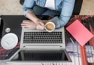 Yukardan tanınmayan, gündelik kıyafetleriyle serbest çalışan, lezzetli kahveler içen, renkli masada elinde not defteriyle oturup evde netbook kullanan bir kadın.