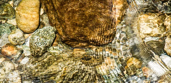Superficie del agua con pequeñas olas de un río con piedras —  Fotos de Stock