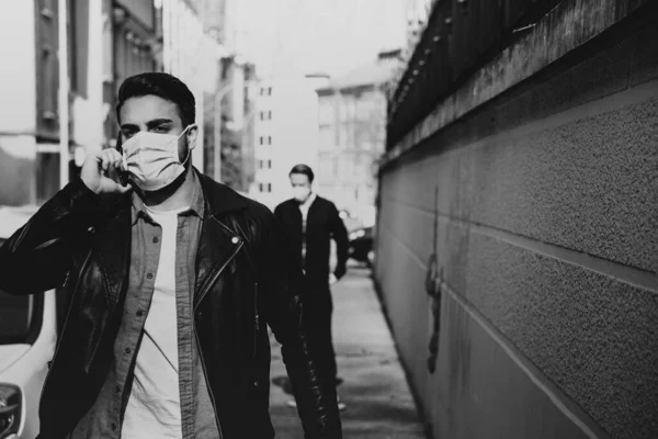 black and white corona - covid-19 concept picture with two men wearing face masks on the streets