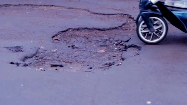 Kobieta z wózkiem i dzieckiem jedzie zniszczoną drogą. Nie naprawiona droga. Pit na chodniku. — Wideo stockowe
