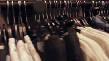 Askılardaki sıra sıra giysiler bir mağazada asılı. Alışveriş merkezinin içini göster.
