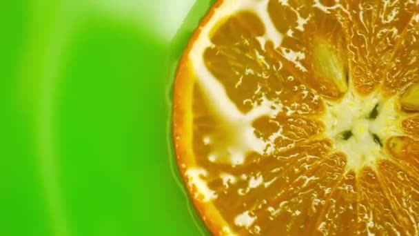 Obrotowy pomarańczowy z zielonym tłem. Piękne światło w wodzie — Wideo stockowe