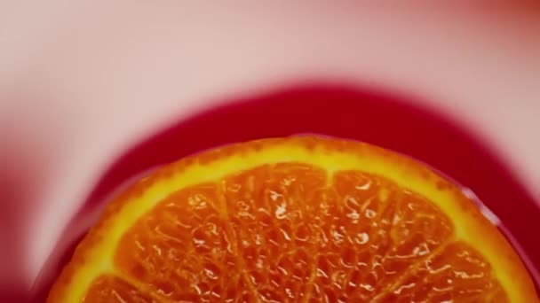 Slice of orange rotating close-up on red background — Stock Video