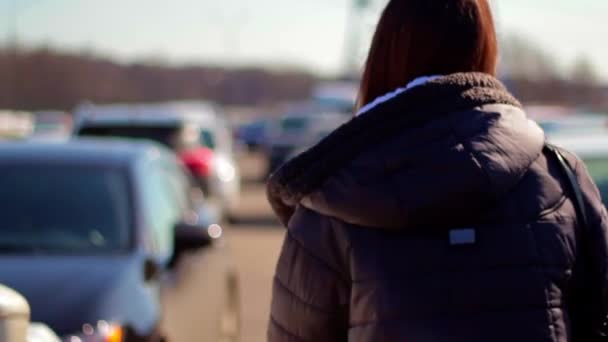 Woman walking in the parking lot. Rear view. — Stock Video