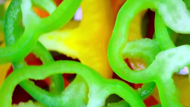 Nahaufnahme. Mehrfarbige Paprika-Scheiben auf rotierendem Hintergrund. Ansicht von oben — Stockvideo