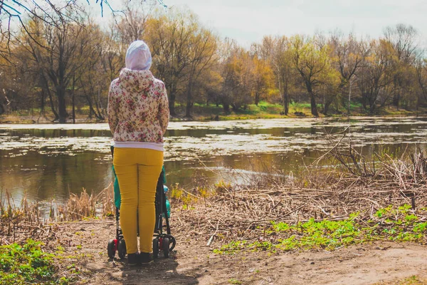Bebekli bir anne baharda gölde bebek arabasında