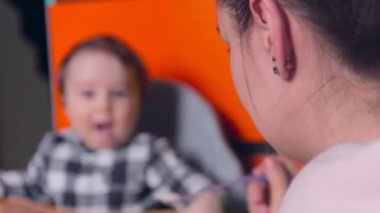 Annem bebeği kaşıkla besliyor. Bebek ağlıyor.