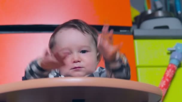 Baby pojke spelar på en barnstol efter att ha ätit — Stockvideo