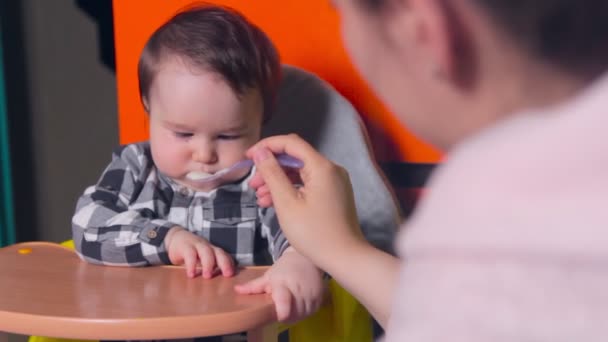 Happy child. Mom feeds her son with a spoon at home — Stock Video