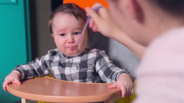 Η μαμά ταΐζει το μωρό με ένα κουτάλι. Το αγοράκι κλαίει. — Αρχείο Βίντεο