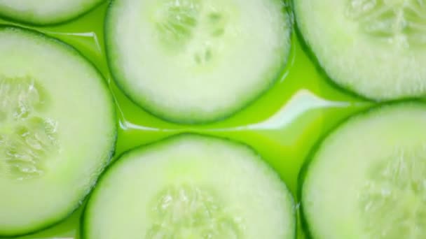 Closeup. slices of cucumbers rotate on a green background. top view — Stock Video