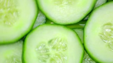 - Yakın çekim. Salatalık dilimleri yeşil arka planda döner. en üstteki görünüm