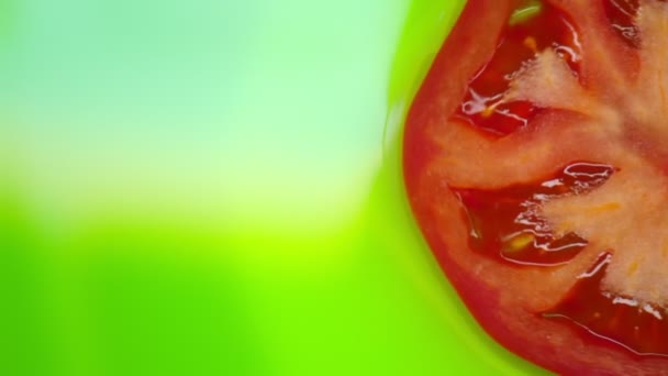 Κοντινό πλάνο. Οι φέτες ντομάτας περιστρέφονται σε πράσινο φόντο. Αντιγραφή χώρου. πάνω όψη. — Αρχείο Βίντεο