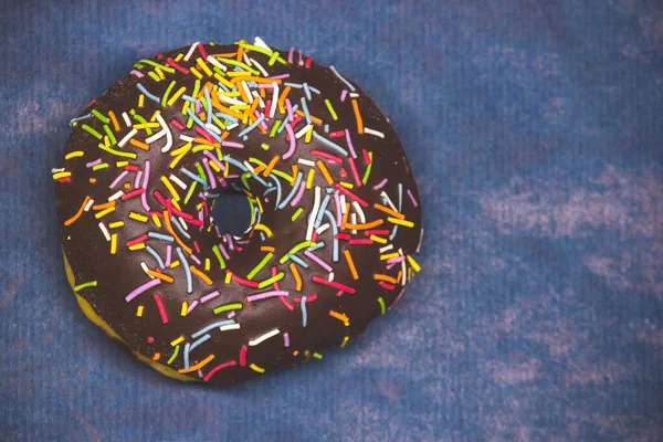 Donut de chocolate em um fundo azul escuro close-up espaço de cópia — Fotografia de Stock