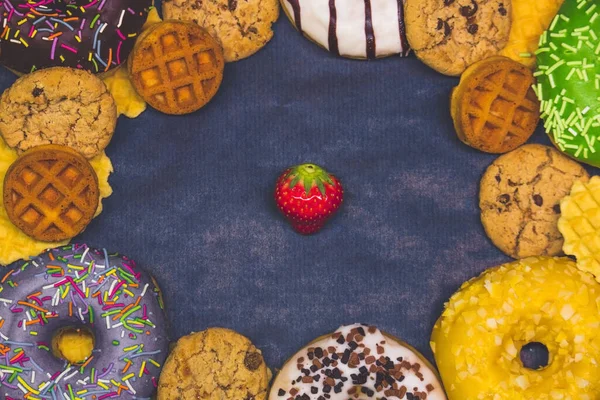 Çilek kopyalama alanı ile koyu mavi bir zemin üzerinde donut, kurabiye ve waffle bileşimi