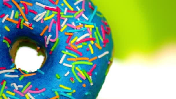 Blue donut with colored sprinkles rotates on a green background copy space — Stock Video