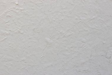 Beton duvardaki eski beyaz çatlak boya. Doku, şekil, arka plan. Duvar boyayla çatladı.