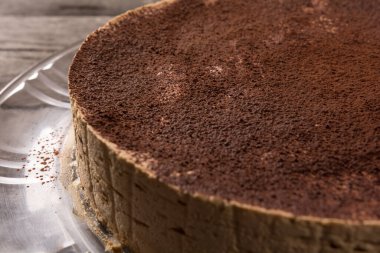 Kırsal bir masada üzerinde çikolata tozu olan tiramisu kekinin yakın çekimi.