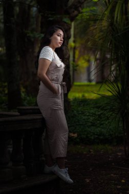 Ormanın ortasında duran genç bir kadın. Karanlık bir ton.