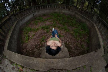 Genç siyah saçlı Latin, tepeden bakan bir parkta oturuyor.