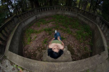 Genç siyah saçlı Latin, tepeden bakan bir parkta oturuyor.