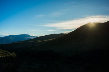 Gün doğumunun ilk ışıkları mavi gökyüzü olan bir dağın yamaçlarında.