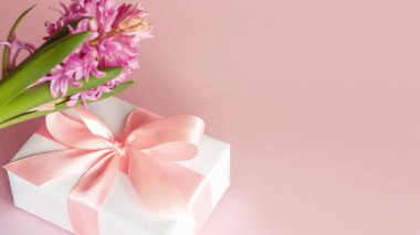 Beyaz hediye ya da pembe arkaplanda pembe kurdele ve sümbül çiçeği olan hediye kutusu. Uzayı kopyala Anneler günün kutlu olsun, kadınlar günü, sevgililer günü veya doğum günü bahar tebrik kartı..