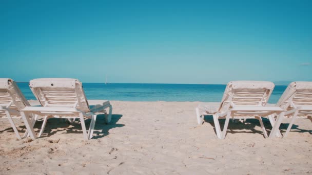 Ligstoelen wachten op toeristen op een schoon strand — Stockvideo