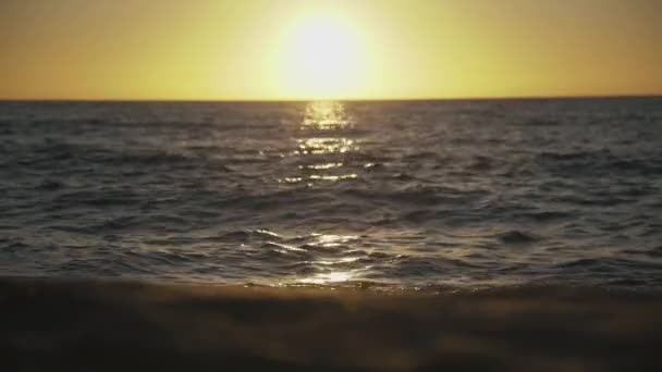 Puesta de sol en el mar reflejándose en la playa y la superficie del agua — Vídeo de stock