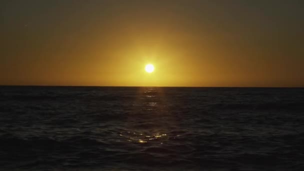 El sol poniente pinta el cielo de amarillo en el mar — Vídeo de stock