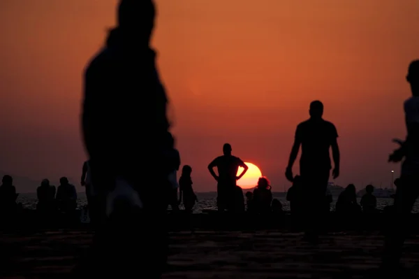 Puesta de sol y personas silueta . — Foto de Stock