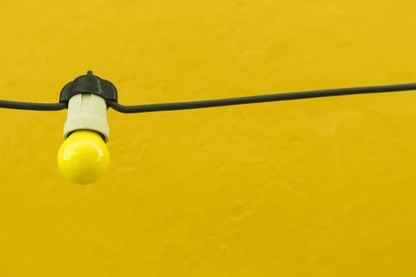 Ampoule jaune sur un mur jaune . — Photo