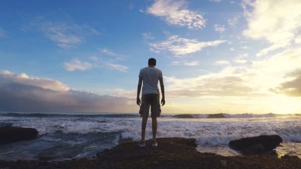 20s homem pulando com as ondas perto do oceano e sobre as rochas. Filmagem em câmara lenta . — Vídeo de Stock