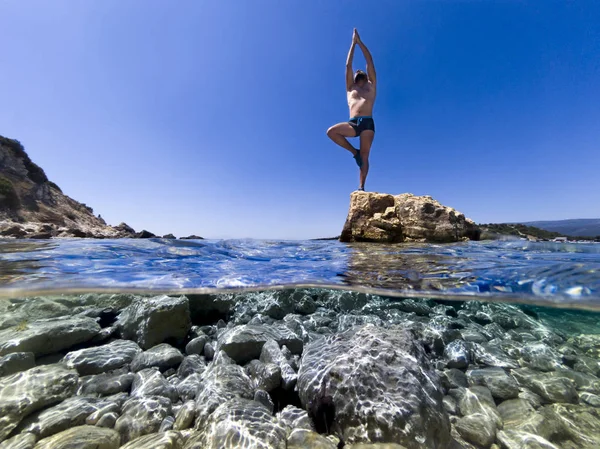 Man stands balanced on a rock on one foot. — Stock Photo, Image