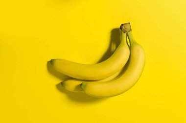 Sarı bir arka plan üzerinde üç muz.