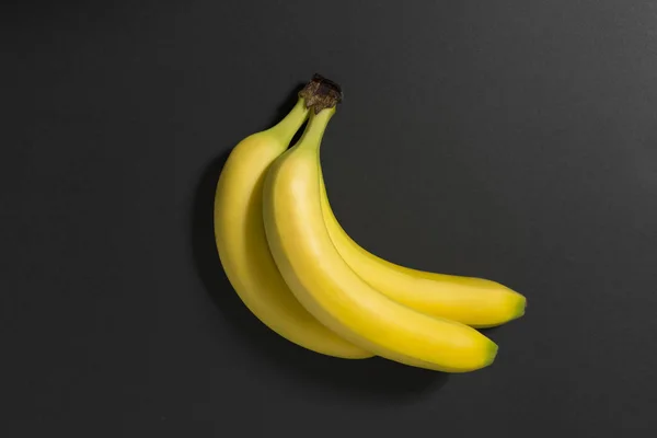 Tre bananer på en svart bakgrund. — Stockfoto