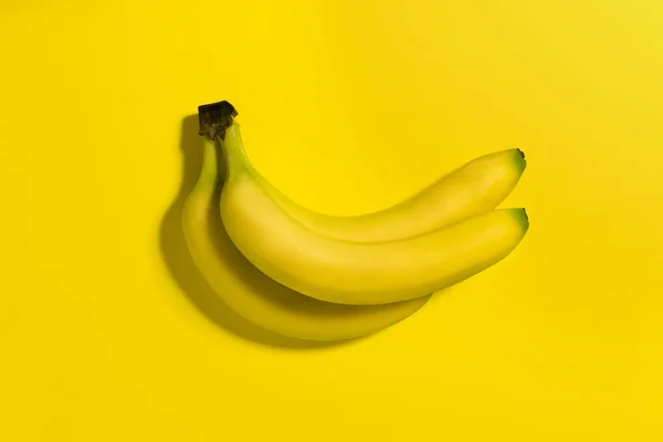 Trzy banany na żółtym tle. — Zdjęcie stockowe