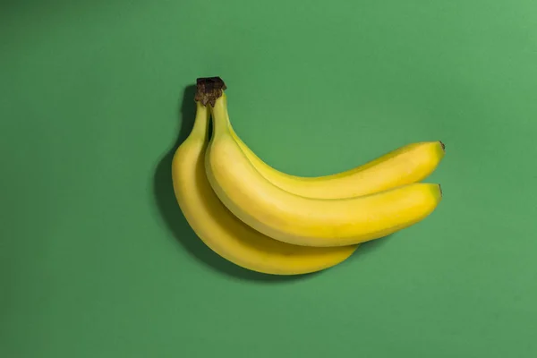 Trzy banany na zielonym tle. — Zdjęcie stockowe