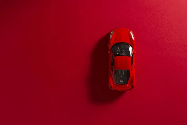 Червоний іграшковий автомобіль на червоному тлі. — стокове фото