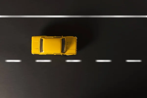 Gele speelgoedauto op een zwarte achtergrond. — Stockfoto