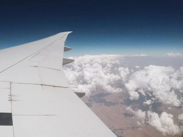 Plane's wing and clouds over the land. — Stock Photo, Image