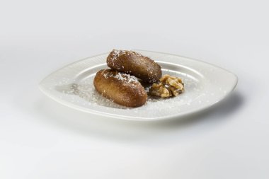 Bilenmiş yumurta şekilli tatlı hamur işleri beyaz tabakta ve bir whit üzerinde