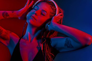 Ağaç örgülü saçlı ve kulaklıkla dans eden DJ kadın..