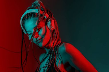 Ağaç örgülü saçlı ve kulaklıkla dans eden DJ kadın..