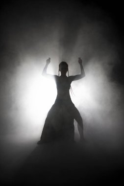Siluet dansçısı kadın sis içinde dans figürleri sergiliyor..