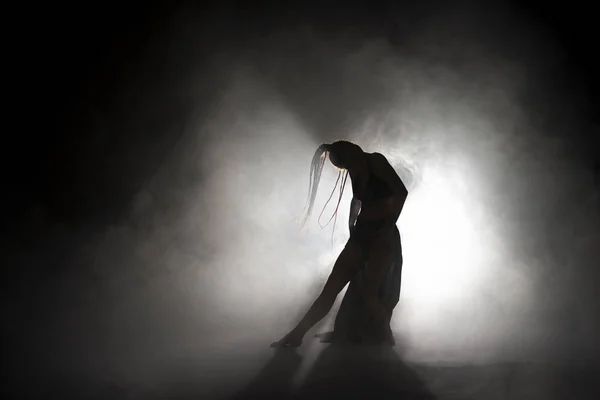 Silueta bailarina mujer realizando figuras de baile en la niebla . — Foto de Stock