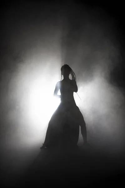 Siluet dansçısı kadın sis içinde dans figürleri sergiliyor.. — Stok fotoğraf